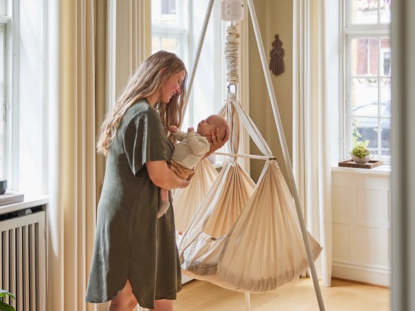 Mutter mit Baby vor einer Membantu Federwiege im Wohnzimmer